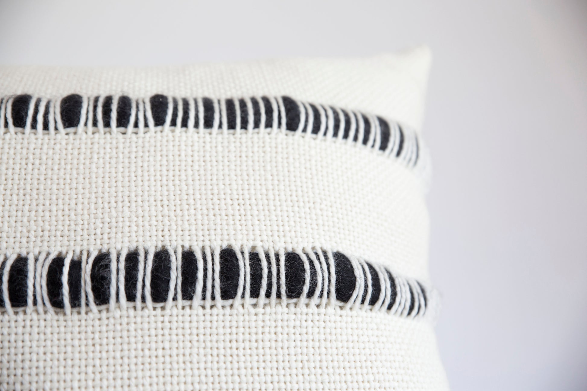 Textured pillow cover hand loomed in merino wool with stripes of roving in black - Close shot corner