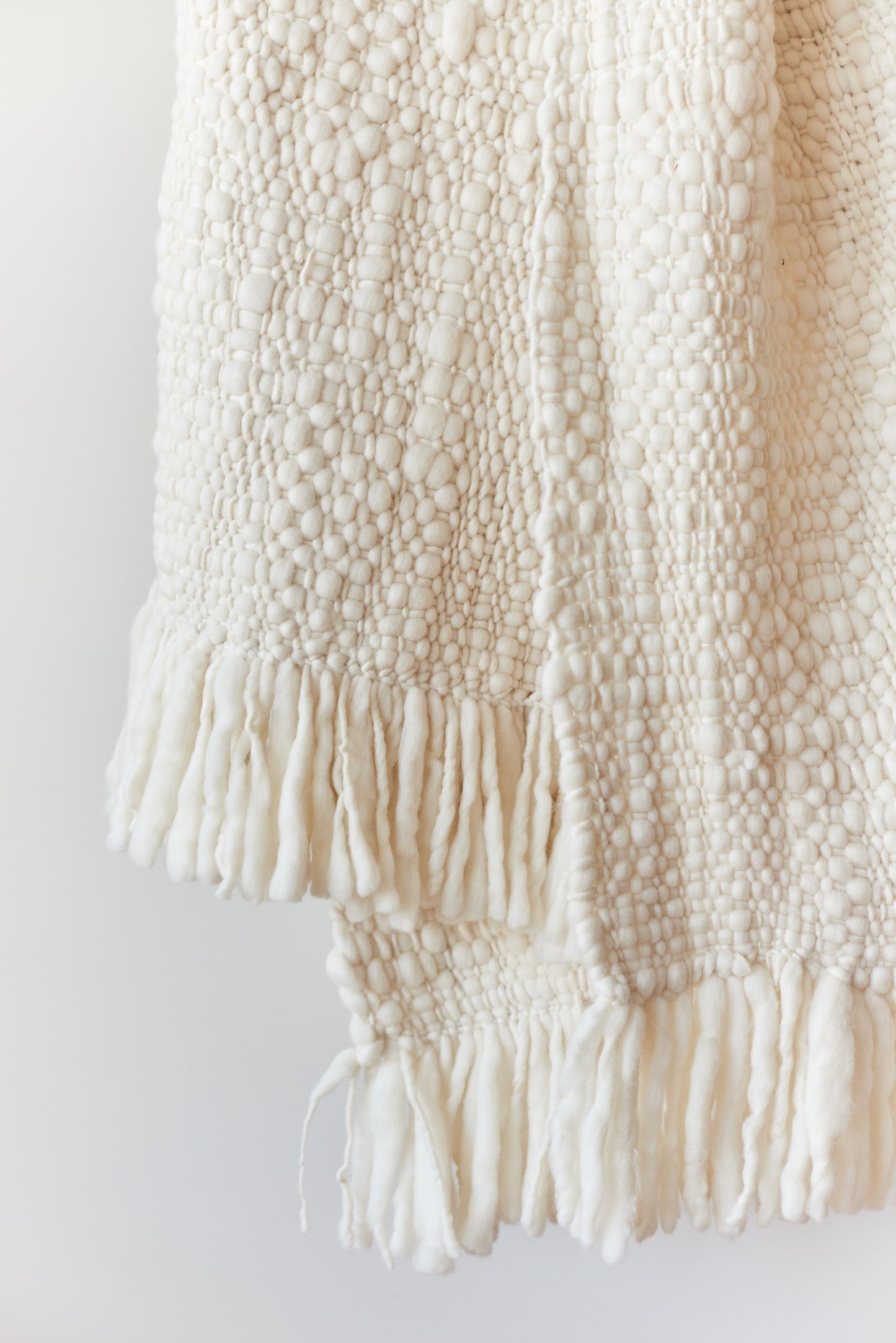 Detail of soft undyed Merino wool weave of the Nube blanket, handwoven slowly in Uruguay.