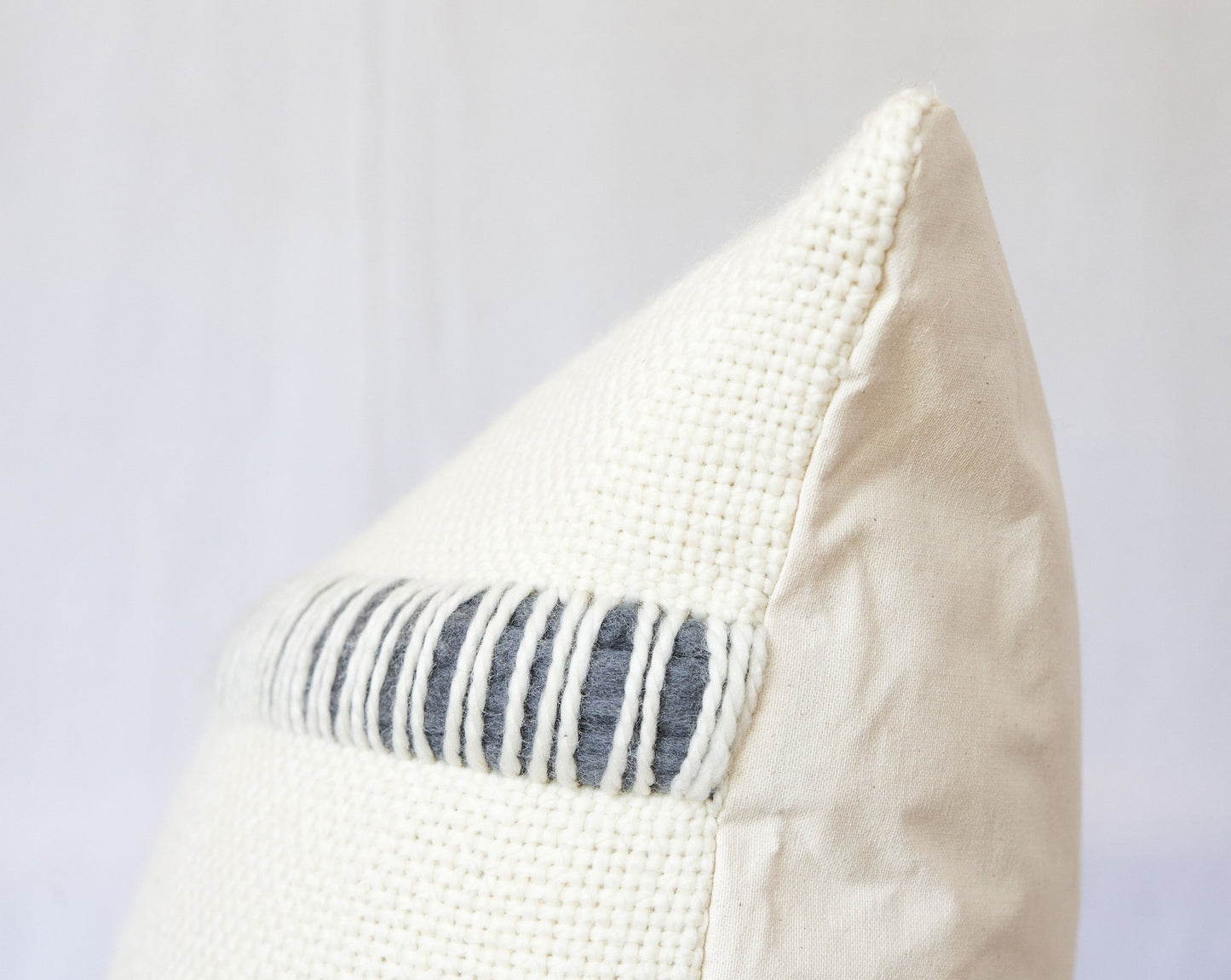 Both sides of cream pillow cover with hand woven grey roving merino wool stripes at the front and organic cotton at te back