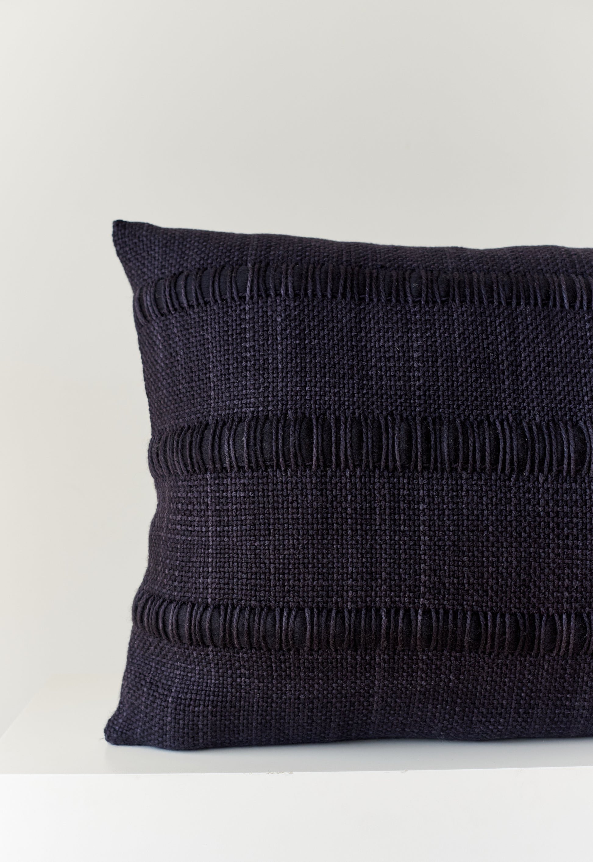 Part of handwoven black wool pillow with roving yarn like stripe