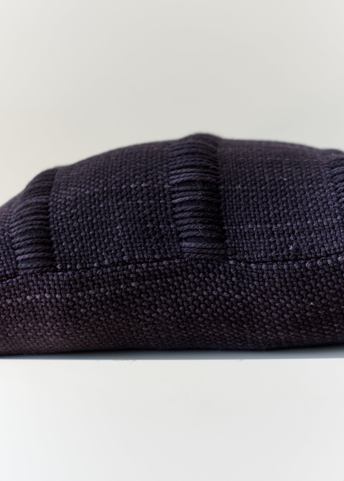 partial horizontal view of a black pillow handwoven