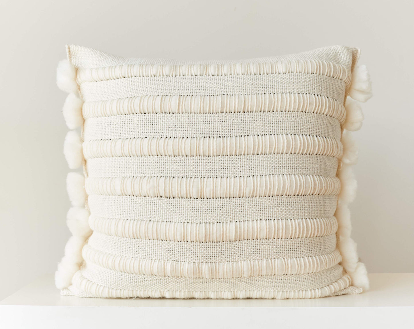 Throw pillow cover hand weaving with chunky stripes and pom poms in natural merino wool